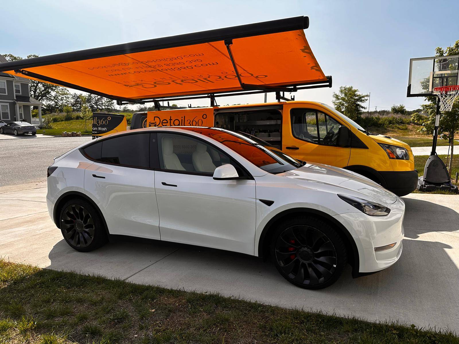 White Tesla Model Y parked under the Car Detail 360 van awning